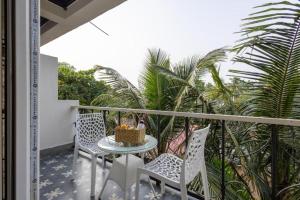 a balcony with a table and chairs and palm trees at The Baga Pescador in Baga