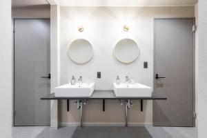 two sinks in a bathroom with two mirrors at The Elysian Retreat in Otaru