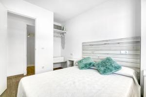 a bedroom with a white bed with two green pillows at Bonaire in Gandía +14 photos