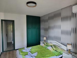 a bedroom with a green bed and a mirror at Villa Malazzo in Balatongyörök