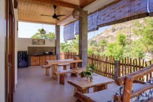 a porch with wooden tables and benches and a kitchen at Amed Sudi House in Amed