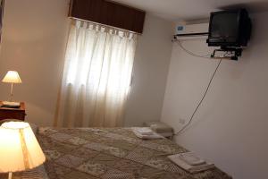 a bedroom with a bed with a television and a window at Departamentos San Jorge in Santa Rosa