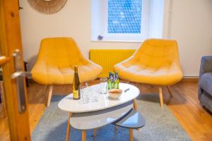 two orange chairs and a table with a bottle and glasses at Le Chalet Cozy & Spa in Wildersbach