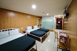 a hotel room with two beds and a table and chairs at Hotel Uno in Davao City