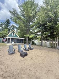 a group of chairs sitting in the sand in front of a house at FRIENDLY INN LIMIT 5 cottage in North Sebago
