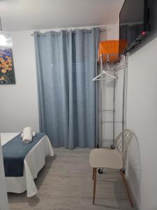 a bedroom with a bed and a chair and a television at H SENDA ReAL in Alcuéscar