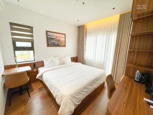 a bedroom with a bed and a desk and a window at Verdant Apartment & Hotel in Dong Hoi +6 photos