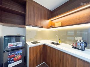 a small kitchen with a refrigerator and a sink at Verdant Apartment & Hotel in Dong Hoi