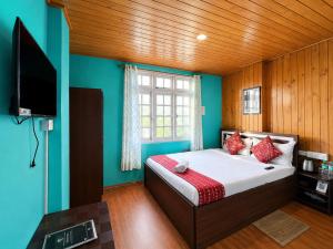 a bedroom with a bed with blue walls and a television at Hotel Pinecrest Inn Darjeeling With Mountain View Room And Parking - Restaurant Facility in Darjeeling
