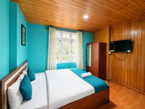 a bedroom with a bed with blue walls and a window at Hotel Pinecrest Inn Darjeeling With Mountain View Room And Parking - Restaurant Facility in Darjeeling