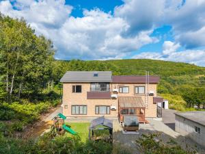 an aerial view of a house with a hill in the background at The Elysian Retreat in Otaru
