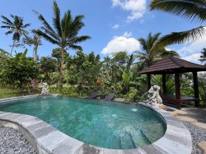 a swimming pool in a resort with a gazebo at Pondok Risky in Tegalalang