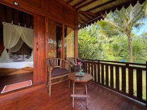 a wooden porch with a chair and a table at Pondok Risky in Tegalalang