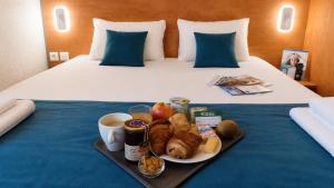 a tray of breakfast food on a bed at BRIT HOTEL Caen Hérouville in Hérouville-Saint-Clair