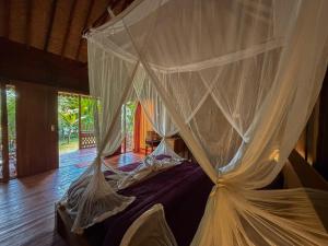 a canopy bed with white drapes in a room at Pondok Risky in Tegalalang