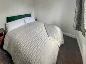 a bedroom with a white bed with a green headboard at Ashby Meadows in Spilsby +6 photos