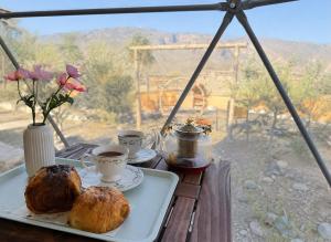 a table with two cups of coffee and croissants at Jabal shams domes in Sa‘ab Banī Khamīs