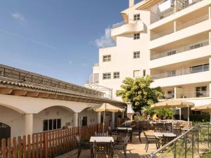 an outdoor patio with tables and chairs in front of a building at Ona Garden Lago in Port d'Alcudia