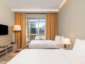 two beds in a hotel room with a large window at Mercure Makkah Aziziah in Mecca +84 photos