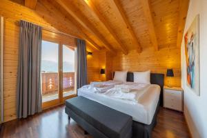 a bedroom with a large bed and a large window at Chalet La Tirelire in Nendaz
