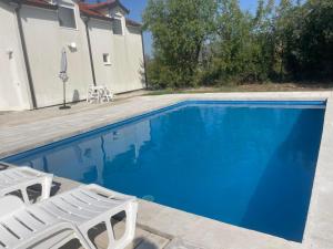 a swimming pool with two lawn chairs next to a house at Amra in Počitelj