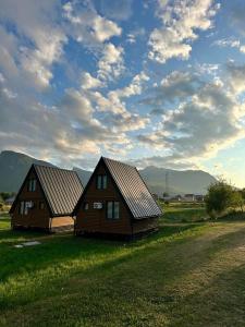 two houses in a field under a cloudy sky at Agin Konak in Gusinje