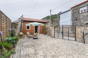a courtyard of a house with a patio and an umbrella at Casa do Monte - Monção in Poças do Monte