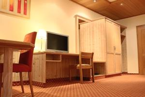 a room with a tv and a chair and a cabinet at Central-Hotel in Winterberg