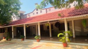 a building with a red roof with potted plants at SERENE Stays - Kjsb farmhouse THANJAVUR in Thanjāvūr +37 photos