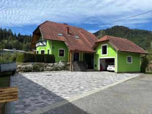 a green house with a red roof and a driveway at Ferienwohnung Grünblick am Katschbach in Teufenbach