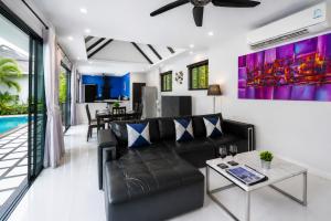 a living room with a black leather couch and a table at Pool Villa Clos Vougeot Tropical Vibe in Ban Saiyuan (1)