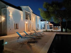 a group of chairs sitting next to a house at night at Vila Nikola in Pučišća