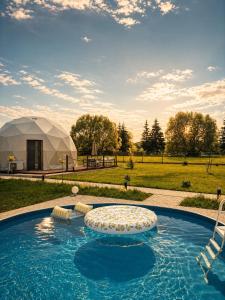 a yurt with a swimming pool and a tent at Glamping nad Sanem in Krzemienna