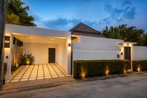 a white house with a driveway at night at Pool Villa Clos Vougeot Tropical Vibe in Ban Saiyuan (1)