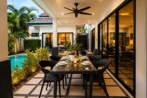 a dining table on the patio of a house at Pool Villa Clos Vougeot Tropical Vibe in Ban Saiyuan (1) +3 photos
