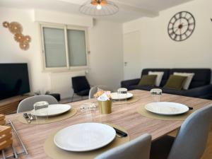 a wooden table with plates and chairs in a living room at L'Appart' in Bruz