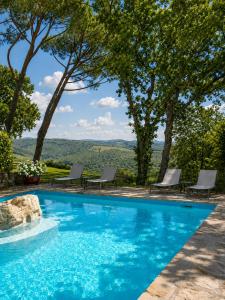 a blue swimming pool with chairs and trees at Borgo Livernano in Radda in Chianti +37 photos