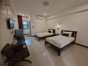 a bedroom with two beds and a tv in it at Erawan Place in Mae Sot