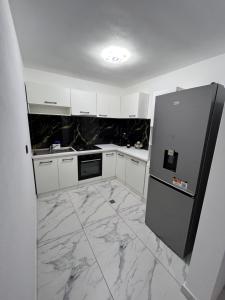 a kitchen with white cabinets and a black refrigerator at Căsuța Găvruj in Săcel +10 photos