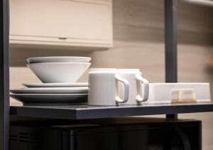 a table with two mugs and plates and a bowl at Heritage Collection on KG - Mobile App Check-In in Singapore