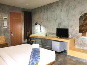 a bedroom with a bed and a desk with a television at Tanisa Resort in Na Dhung