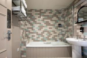 a bathroom with a tub and a sink at The White Lion in Tenterden