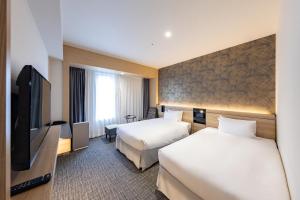 a hotel room with two beds and a flat screen tv at Hotel Keihan Sendai in Sendai