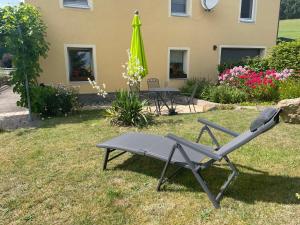 a chair and an umbrella in the yard of a house at Am Holundergrund in Kurort Gohrisch
