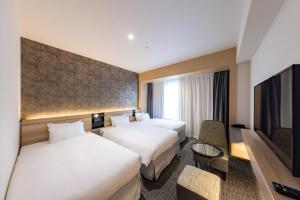 a hotel room with two beds and a flat screen tv at Hotel Keihan Sendai in Sendai +61 photos