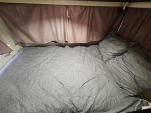 an unmade bed in the back of a van at Full Service Caravan 1 in Albertslund