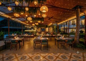 a restaurant with tables and chairs and chandeliers at Blu Missel By The River in Panaji