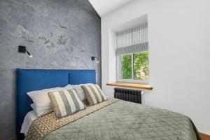 a bedroom with a bed with a blue headboard and a window at Homly S22 in Riga