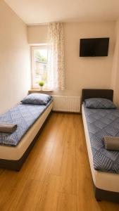a bedroom with two beds and a window with a tv at Pokoje Bielsko in Bielsko-Biała