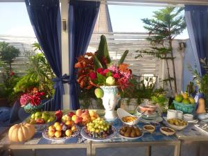 a table with plates of fruit and a vase of flowers at Hotel Palladio in Giardini Naxos